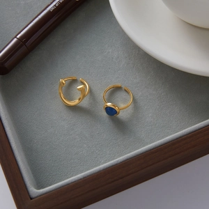 Close-up of a gold-plated ring set with a blue gemstone on a luxury velvet tray