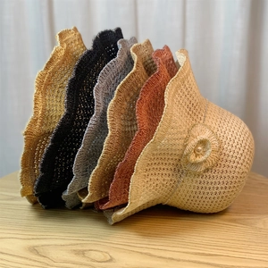Close-up of stacked breathable straw sun hats with wavy edges and floral details in multi-colors