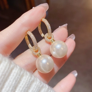 Detailed macro of gold pearl drop earrings with sparkling micro-pave cubic zirconia crystals