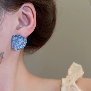 Close-up of blue resin earring with ore texture worn on ear highlighting unique design