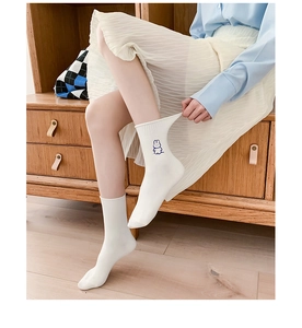Close-up of white cotton crew socks featuring a minimalist blue cartoon bunny design