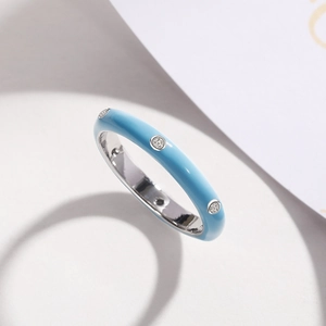Detail of light blue enamel ring featuring three inlaid cubic zirconia on a silver band