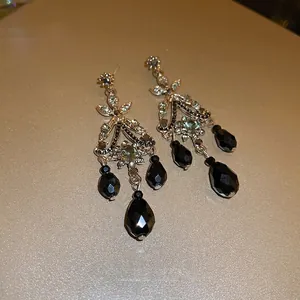 Vintage silver crystal earrings with black teardrop tassels on champagne background