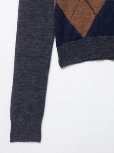 Macro detail of knit polo shirt sleeve with argyle pattern and ribbed texture cuffs