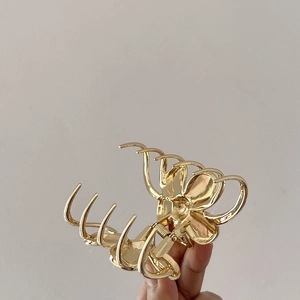 Close-up of golden alloy flower hair claw clip showing intricate floral design details