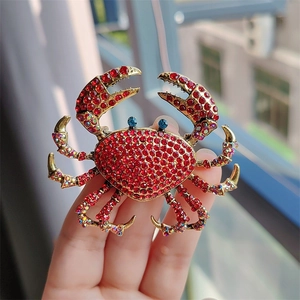 Macro shot of crab brooch with red rhinestones and blue eyes held in hand