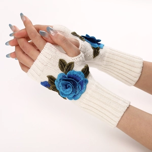 Detail of cable knit texture and blue floral embroidery on warm fingerless gloves
