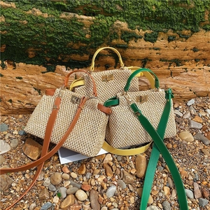 Three woven straw beach bags with leather trim and metal turn-lock closures in outdoor setting