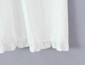 Vue détaillée de l'ourlet de la robe en coton blanc avec volants et texture lin raffinée