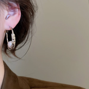 Close-up of hammered texture silver hoop earring with pearl detail on model