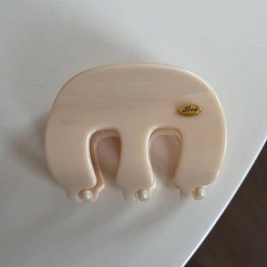 Detailed top view of beige French style claw clip with a golden Love logo on a white table