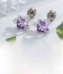 Detail of Saturn-shaped titanium ear stud with purple zircon and silver plating