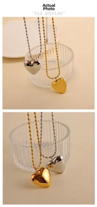 Detailed view of puffed heart pendants in gold and silver finish with bead chains