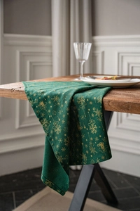 Détail du chemin de table de Noël vert foncé avec motifs dorés sur une table en bois