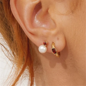 Detail of s925 silver pearl earring with red ruby stone shown on model's ear