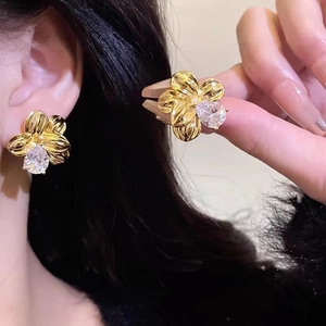 Detailed shot of gold floral earrings featuring textured petals and pear-cut zircon stones