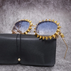 Detail einer Punk-Sonnenbrille mit goldfarbenem Metallrahmen und lila Verlaufsgläsern