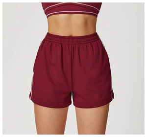 Dettaglio macro dei pantaloncini sportivi bordeaux a vita alta con strisce bianche
