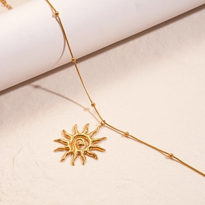 Golden stainless steel necklace featuring a sunburst spiral pendant on a beaded chain