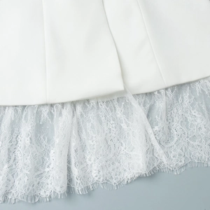 Detail of white blazer hem featuring intricate lace trim and floral embroidery patterns