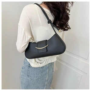Detail view of a black minimalist hobo bag featuring a gold crescent buckle and knotted strap