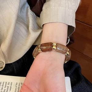 Close-up of beaded acrylic bracelet with brown glitter texture and gold metal spacers