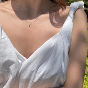 Close-up of a minimalist silver necklace with a tiny zircon pendant on a model