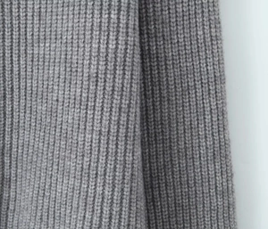Gros plan sur un tricot gris montrant la texture verticale et les mailles de qualité