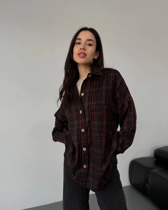 Detail of loose-fit plaid shirt featuring a chest pocket and flannel fabric texture