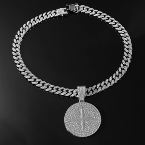 Gros plan sur collier cubain hip-hop argenté avec pendentif croix sur fond noir brillant