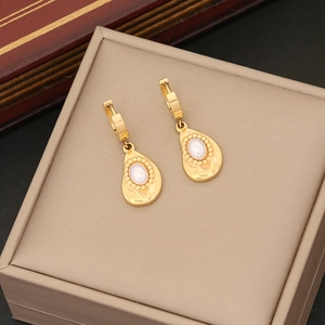 Close-up of elegant gold teardrop earrings with white pearl inlay on a jewelry box