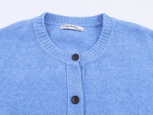 Dettaglio del cardigan in maglia celeste con trama morbida e scollo rotondo con bottoni