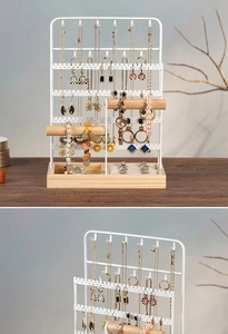 Detail of white metal jewelry organizer with wooden crossbars and jewelry hooks