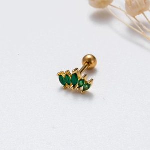 Dettaglio macro del piercing helix dorato con cinque zirconi verdi taglio marquise