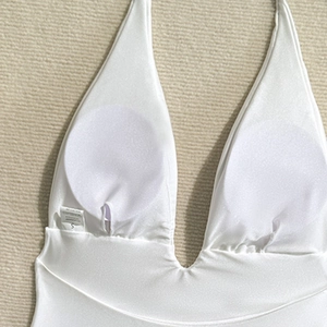Detail view of white shiny fabric swimsuit with removable pads and size S label
