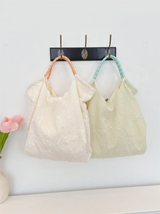 Detail of floral embroidery and unique checkered ring handles on canvas tote bags
