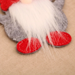 Close-up of handmade Christmas gnome cutlery holder with red felt and plush white beard