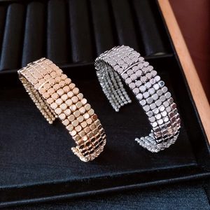 Detail of gold and silver multi-layer beaded metal bracelets on a black jewelry tray