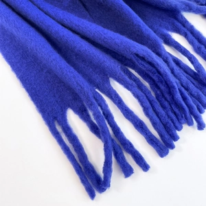 Close-up detail of soft blue mohair scarf with fluffy fringe texture on white background