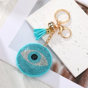 Macro shot of evil eye keychain with blue rhinestones, gold hardware, and tassel detail