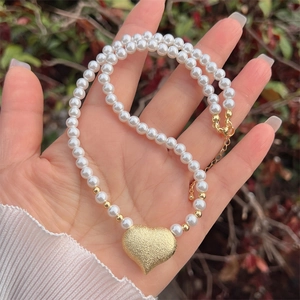 Frosted heart pendant pearl necklace with 18K gold plated clasp shown in hand