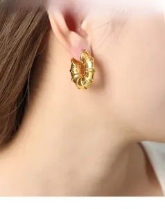 Detailed close-up of golden U-shaped earrings with twisted bamboo texture on model