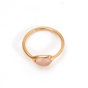 Détail d'un quartz rose irrégulier serti dans une bague dorée minimaliste en acier