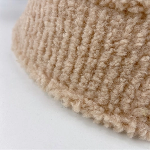 Close-up of thick beige lamb wool fabric texture showing soft fuzzy material details