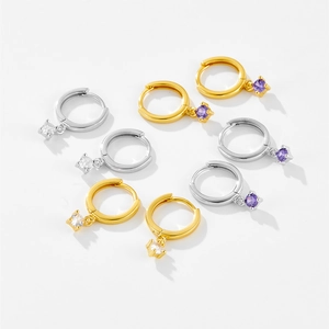 Detail of geometric S925 silver hoop earrings with white and purple gem pendants