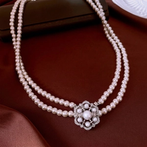 Elegant double-layered pearl necklace with crystal flower clasp on silk background