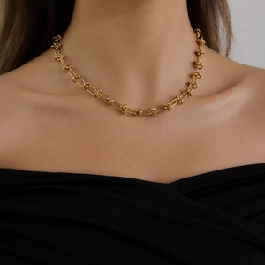 Gouden roestvrijstalen schakelketting met knoopontwerp gedragen voor een moderne stijl