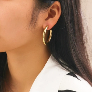 Elegant gold hollow hoop earrings with polished finish worn by a model in a side view