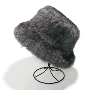 Detail of dark gray faux fur bucket hat with dense texture on a black display stand