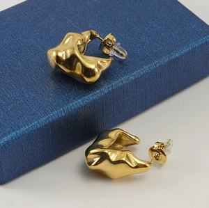 Detailed macro view of gold-plated stainless steel earrings with irregular geometric texture
